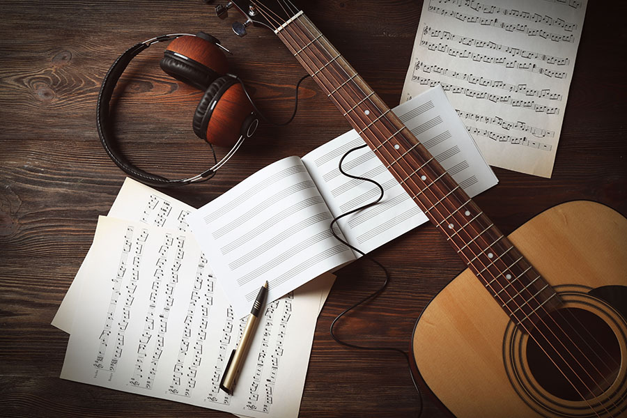 Sheet music, a guitar and headphones: Here someone is just rehearsing a cover song.