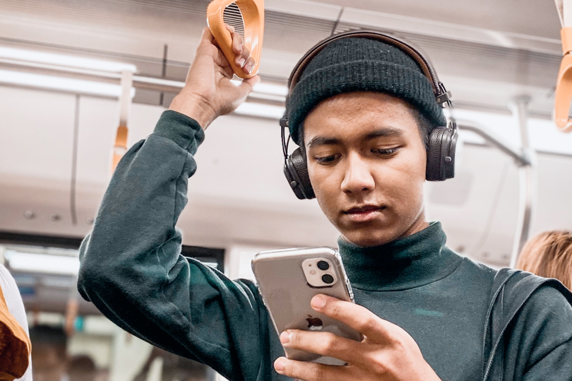 Ein Mann steht in der U-Bahn mit einem Handy in der Hand. Er schaut sich die Gesangsübungen App an.