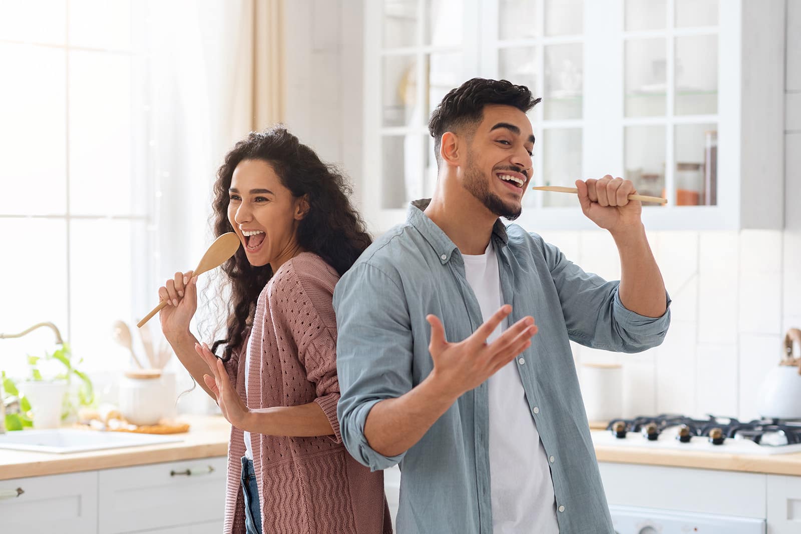 A young couple sings in the kitchen: learning to sing online is fun, for example with the singing app